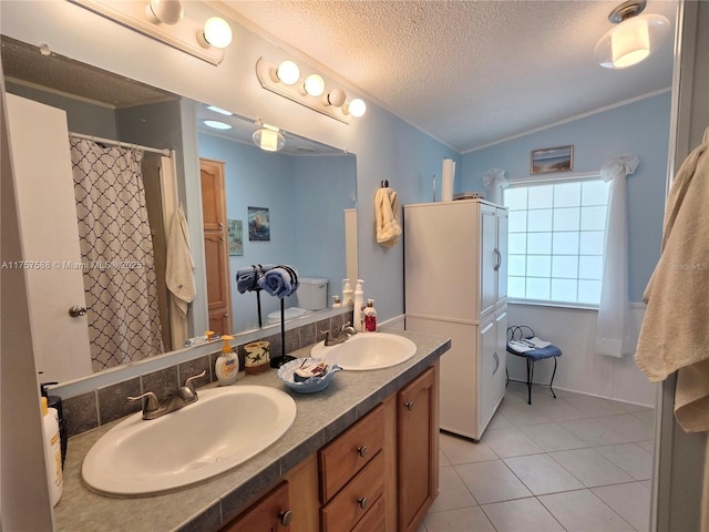 bathroom featuring double vanity, a sink, a textured ceiling, and tile patterned floors