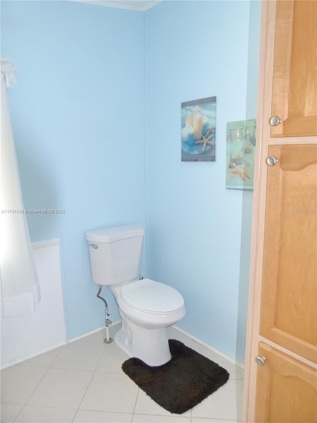 bathroom with baseboards, toilet, and tile patterned floors