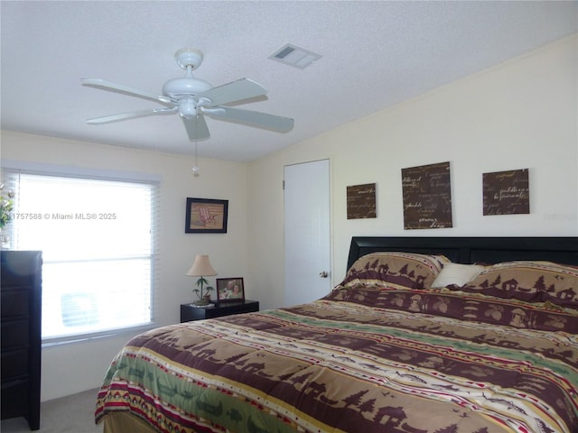 bedroom featuring carpet, visible vents, a ceiling fan, vaulted ceiling, and a textured ceiling