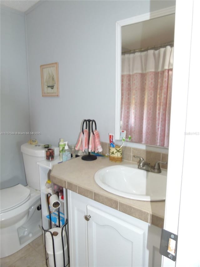 bathroom with toilet, vanity, and tile patterned floors