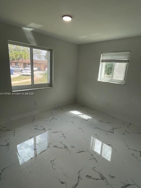 unfurnished room featuring marble finish floor and plenty of natural light