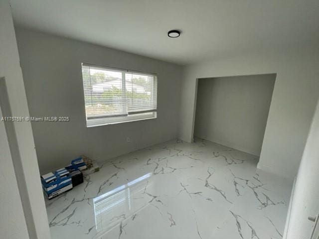 unfurnished bedroom with marble finish floor and a closet