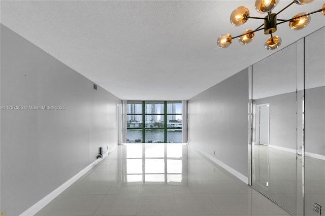 empty room featuring expansive windows, baseboards, a textured ceiling, and tile patterned floors