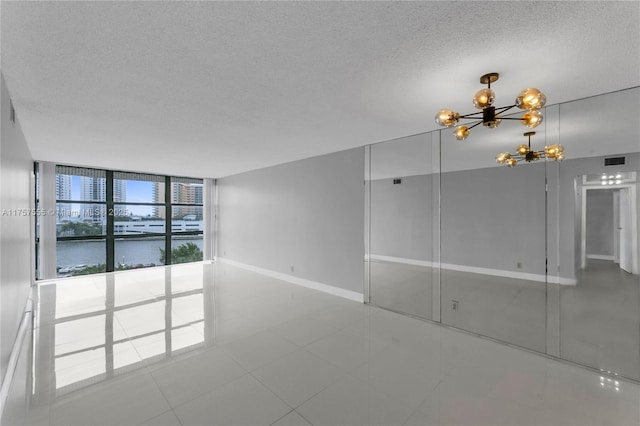 spare room featuring baseboards, visible vents, an inviting chandelier, expansive windows, and a textured ceiling