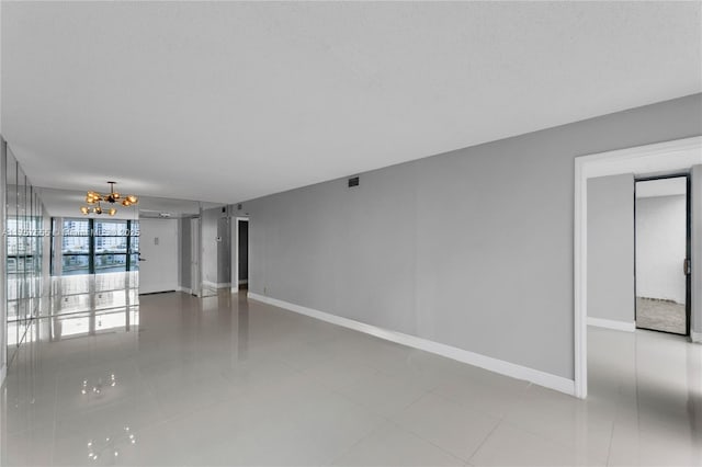 unfurnished living room with tile patterned flooring, visible vents, baseboards, and a notable chandelier