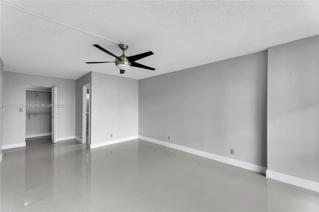 spare room with a ceiling fan, a textured ceiling, and baseboards