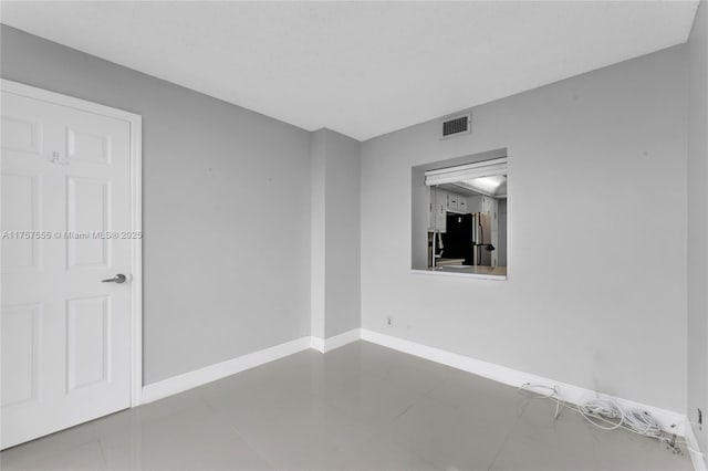 unfurnished room featuring tile patterned flooring, visible vents, and baseboards