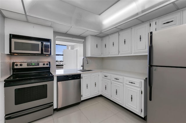 kitchen with appliances with stainless steel finishes, light countertops, a sink, and white cabinetry