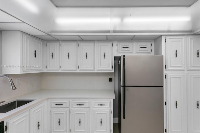 kitchen featuring freestanding refrigerator, white cabinets, and a sink