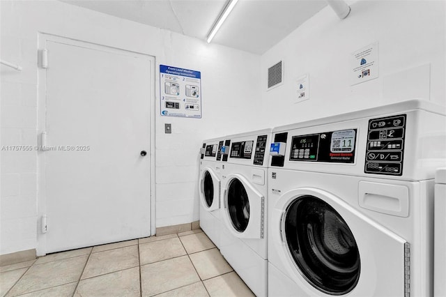 common laundry area with light tile patterned floors and washing machine and dryer