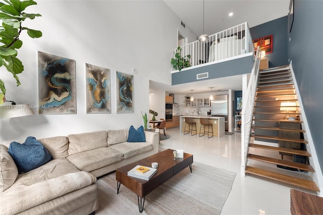 living area with stairs, a high ceiling, light tile patterned floors, and visible vents