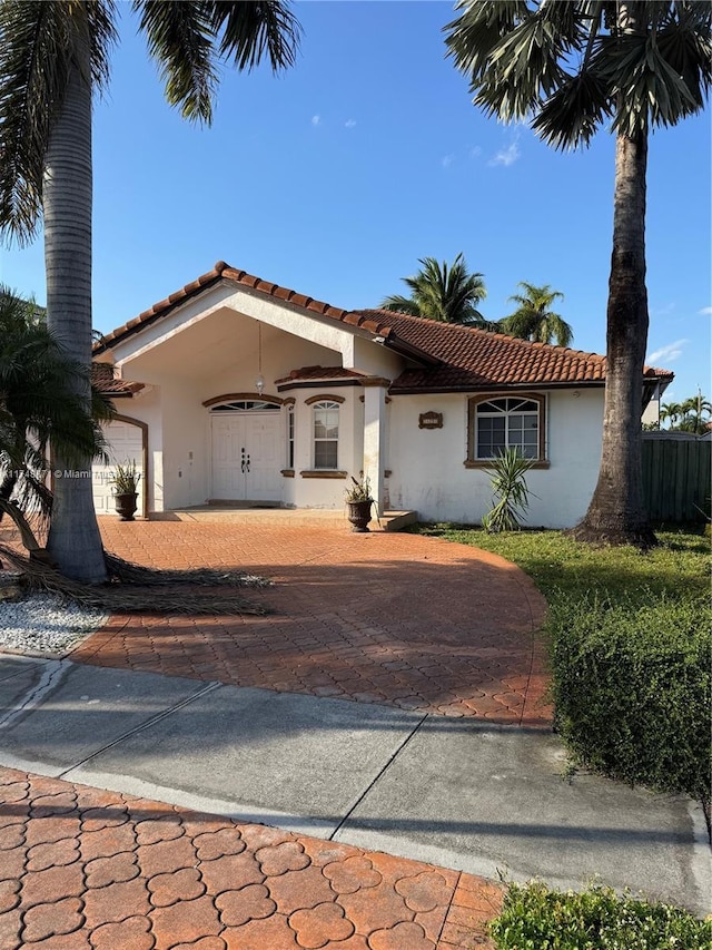 view of front facade with an attached garage, driveway, a tile roof, and stucco siding