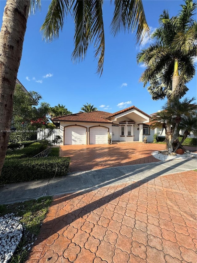 view of front of home with a garage, a tile roof, driveway, and stucco siding
