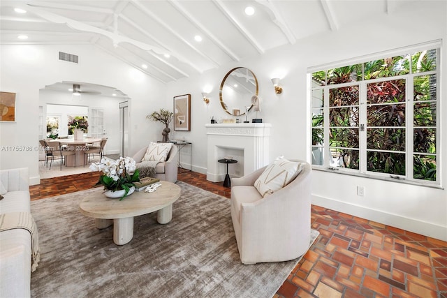 living area with arched walkways, lofted ceiling with beams, visible vents, and baseboards