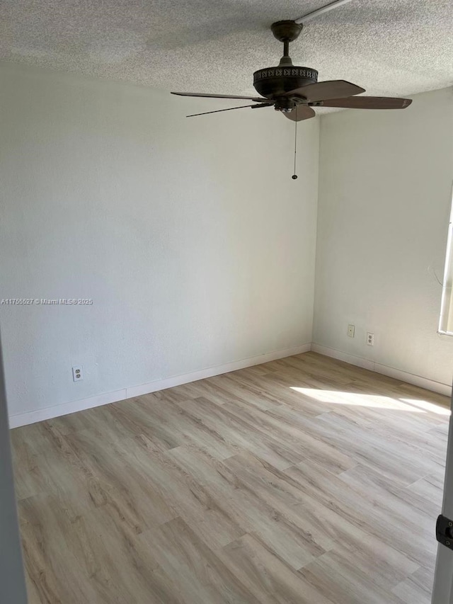 empty room featuring ceiling fan, a textured ceiling, baseboards, and wood finished floors