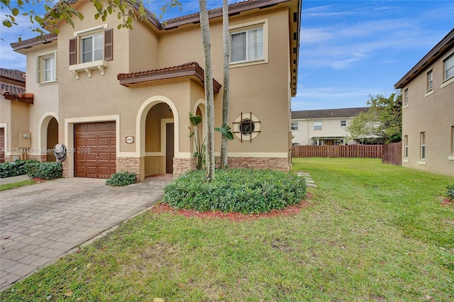 mediterranean / spanish-style home with decorative driveway, stucco siding, an attached garage, fence, and a front lawn