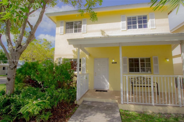 doorway to property with a porch and stucco siding