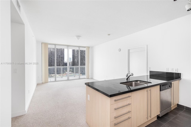 kitchen featuring dark countertops, stainless steel dishwasher, expansive windows, light brown cabinets, and a sink