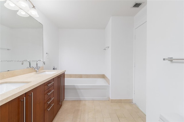 full bathroom with double vanity, a garden tub, visible vents, and a sink