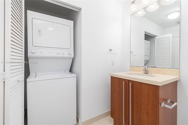 laundry area featuring laundry area, stacked washing maching and dryer, a sink, and baseboards