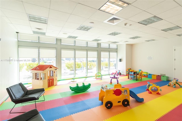 rec room with floor to ceiling windows, visible vents, and a drop ceiling