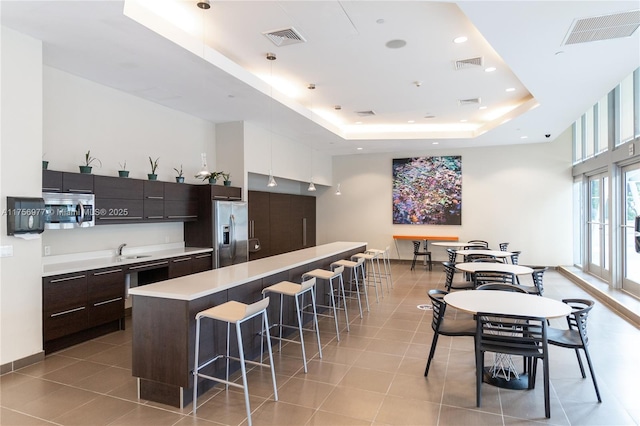 kitchen with stainless steel appliances, a raised ceiling, visible vents, and a kitchen breakfast bar