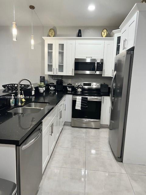 kitchen featuring stainless steel appliances, white cabinetry, a sink, and light tile patterned flooring