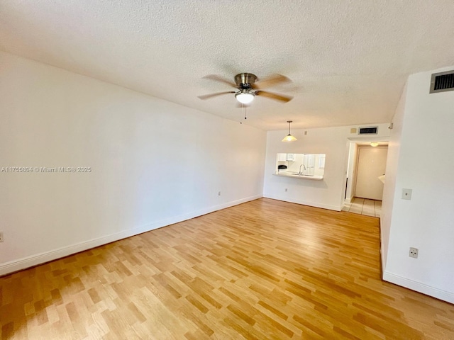 unfurnished living room featuring light wood-type flooring, visible vents, and a ceiling fan