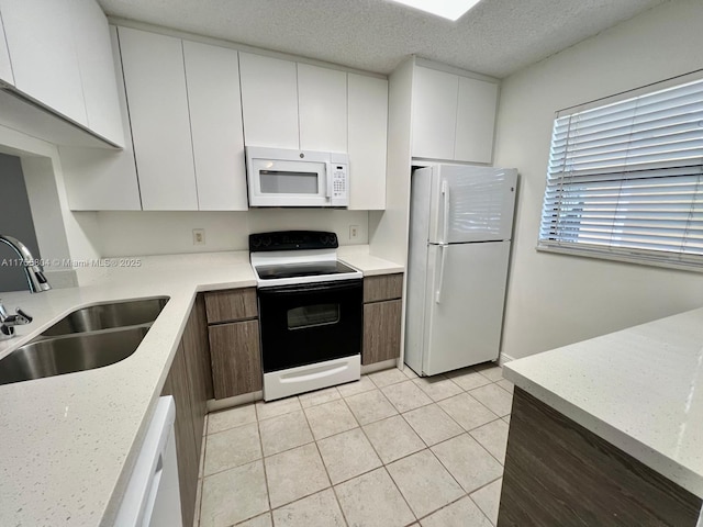 kitchen with white appliances, white cabinetry, a textured ceiling, and a sink