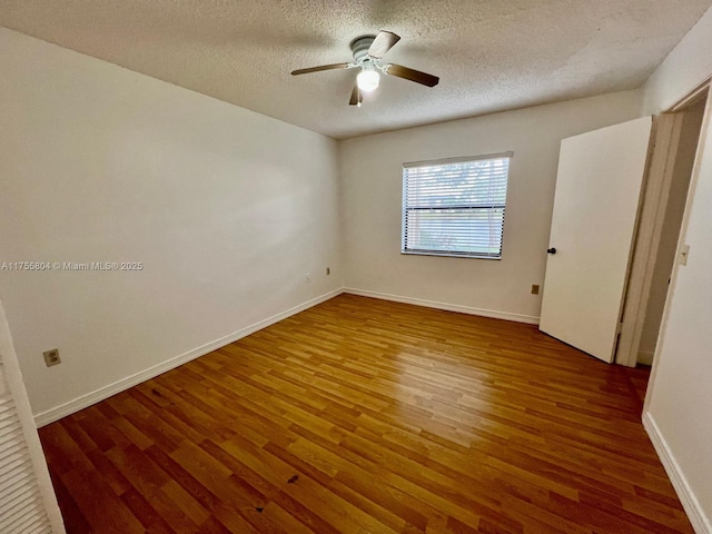 spare room with ceiling fan, baseboards, a textured ceiling, and wood finished floors