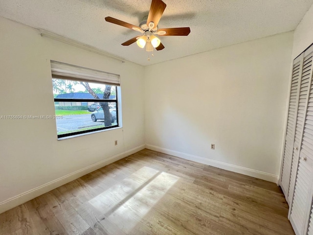 unfurnished bedroom featuring baseboards, light wood-style floors, and a textured ceiling