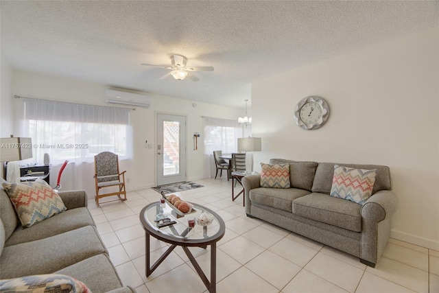 living room featuring a textured ceiling, light tile patterned flooring, ceiling fan with notable chandelier, baseboards, and a wall mounted AC