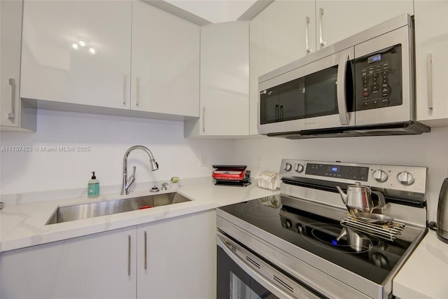 kitchen with appliances with stainless steel finishes, a sink, and white cabinets