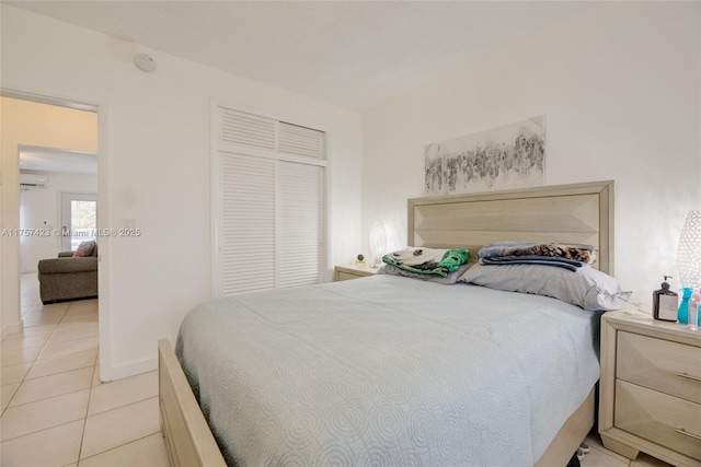 bedroom with light tile patterned floors, a wall mounted AC, a closet, and baseboards