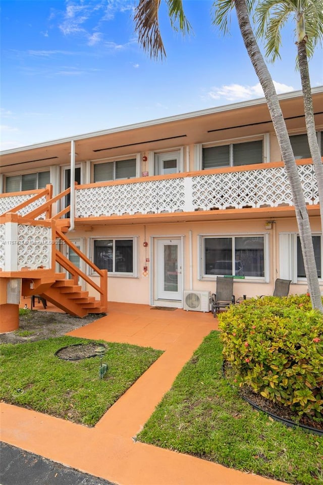 view of front of property with ac unit, stairs, stucco siding, and a patio