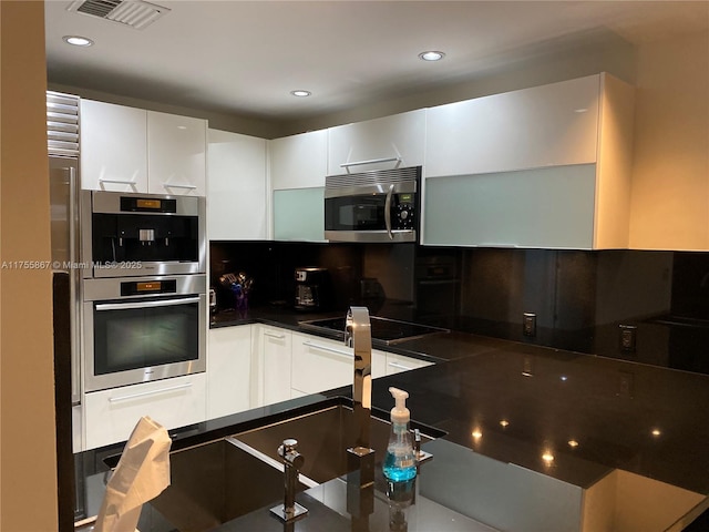 kitchen featuring visible vents, white cabinets, appliances with stainless steel finishes, dark countertops, and modern cabinets