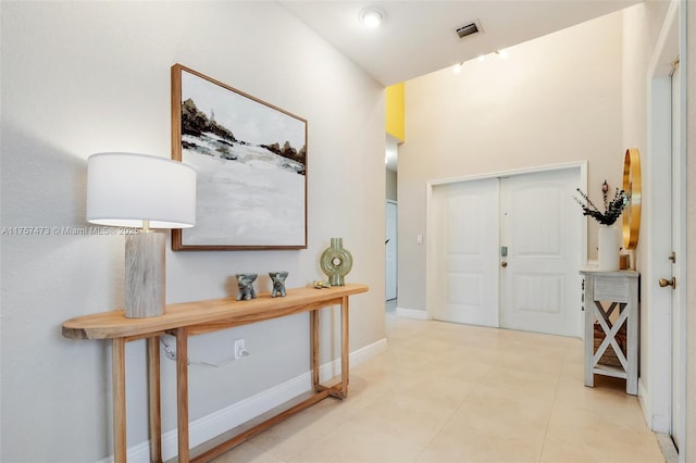 hall featuring visible vents, baseboards, and light tile patterned floors