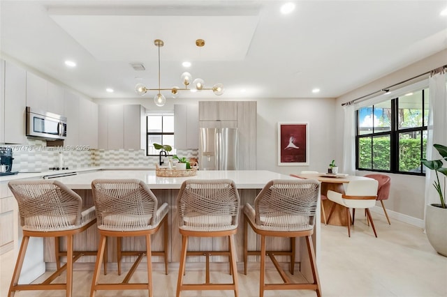 kitchen with light countertops, appliances with stainless steel finishes, decorative backsplash, and a center island