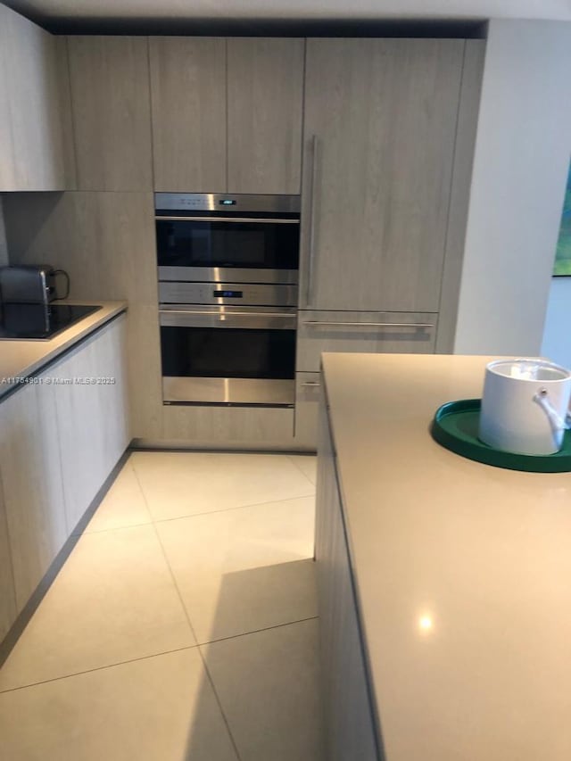 kitchen with light tile patterned floors, modern cabinets, stainless steel double oven, and gray cabinetry