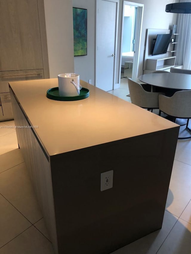 kitchen featuring modern cabinets, a kitchen island, light countertops, and light tile patterned flooring