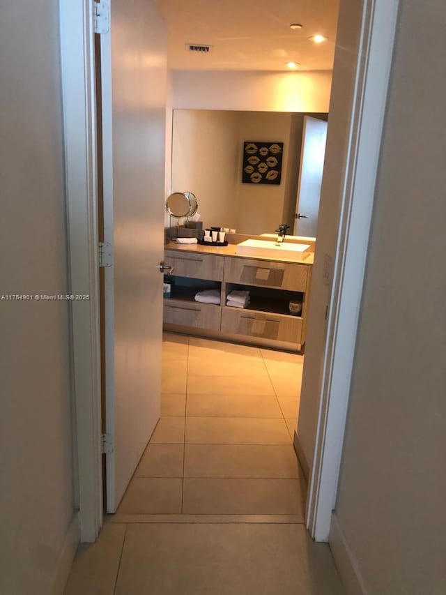 hall featuring tile patterned flooring, visible vents, and a sink