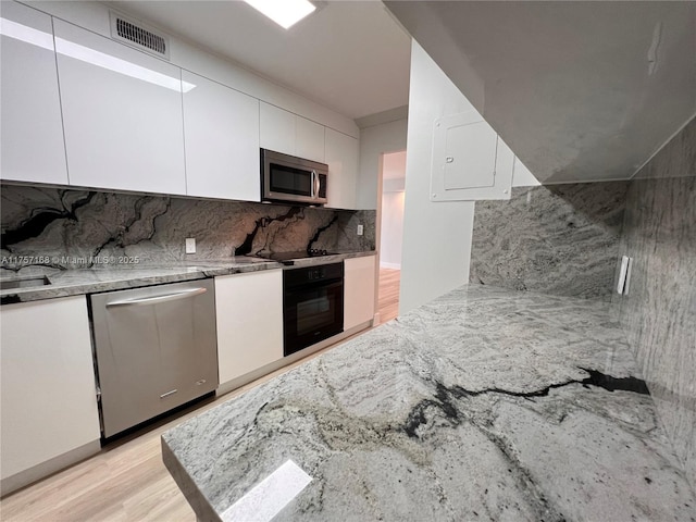 kitchen with tasteful backsplash, visible vents, light wood-type flooring, black appliances, and white cabinetry