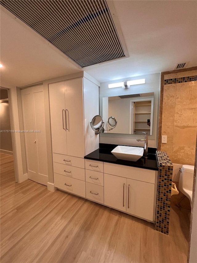 bathroom featuring toilet, visible vents, wood finished floors, and vanity