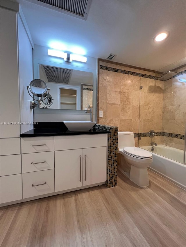 full bathroom featuring shower / bathtub combination, toilet, wood finished floors, vanity, and visible vents