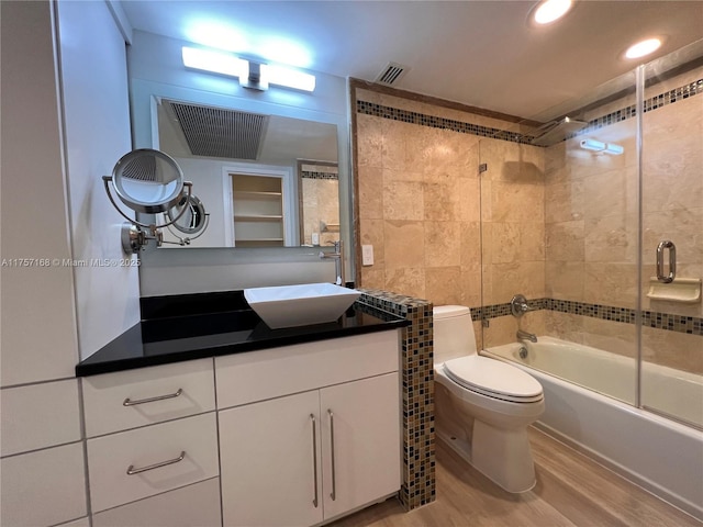 full bath with visible vents, toilet, enclosed tub / shower combo, wood finished floors, and vanity