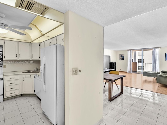 kitchen with visible vents, open floor plan, a sink, a textured ceiling, and white appliances