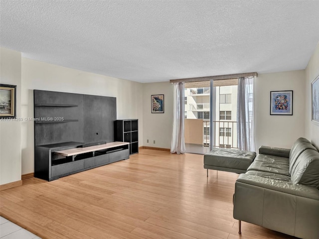 living room with light wood-style floors, baseboards, and a textured ceiling