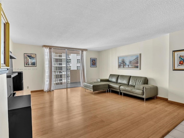 living room with baseboards, light wood-style flooring, and a textured ceiling