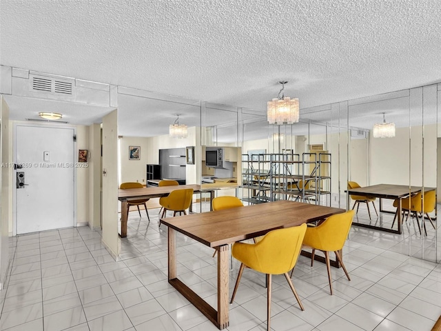 dining space featuring visible vents, a chandelier, and a textured ceiling