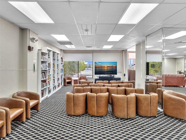 carpeted living area with a drop ceiling